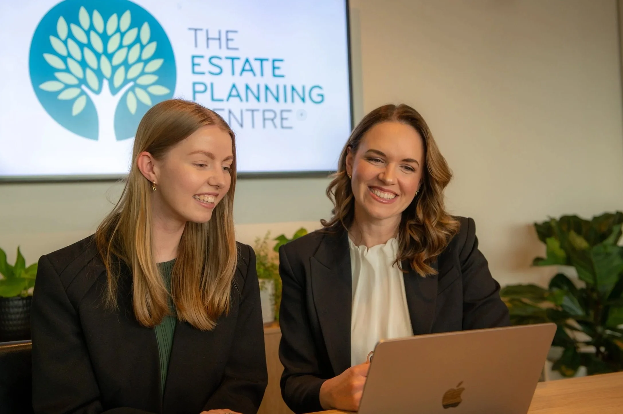 Two members of the team at a meeting table beneath The Estate Planning Centre sign