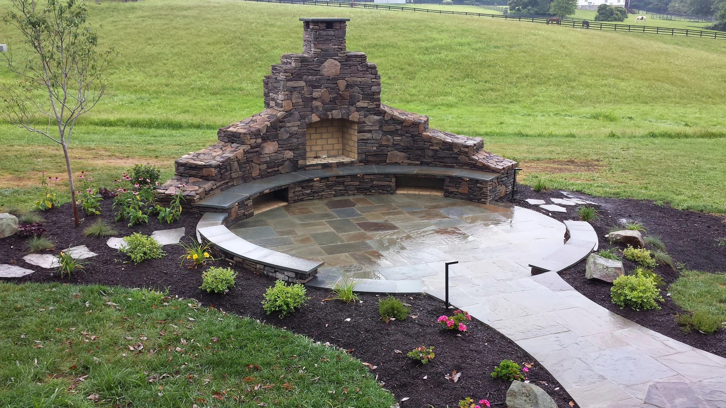 Outdoor fireplace with flagstone patio, walkway, sitting wall and landscaping.