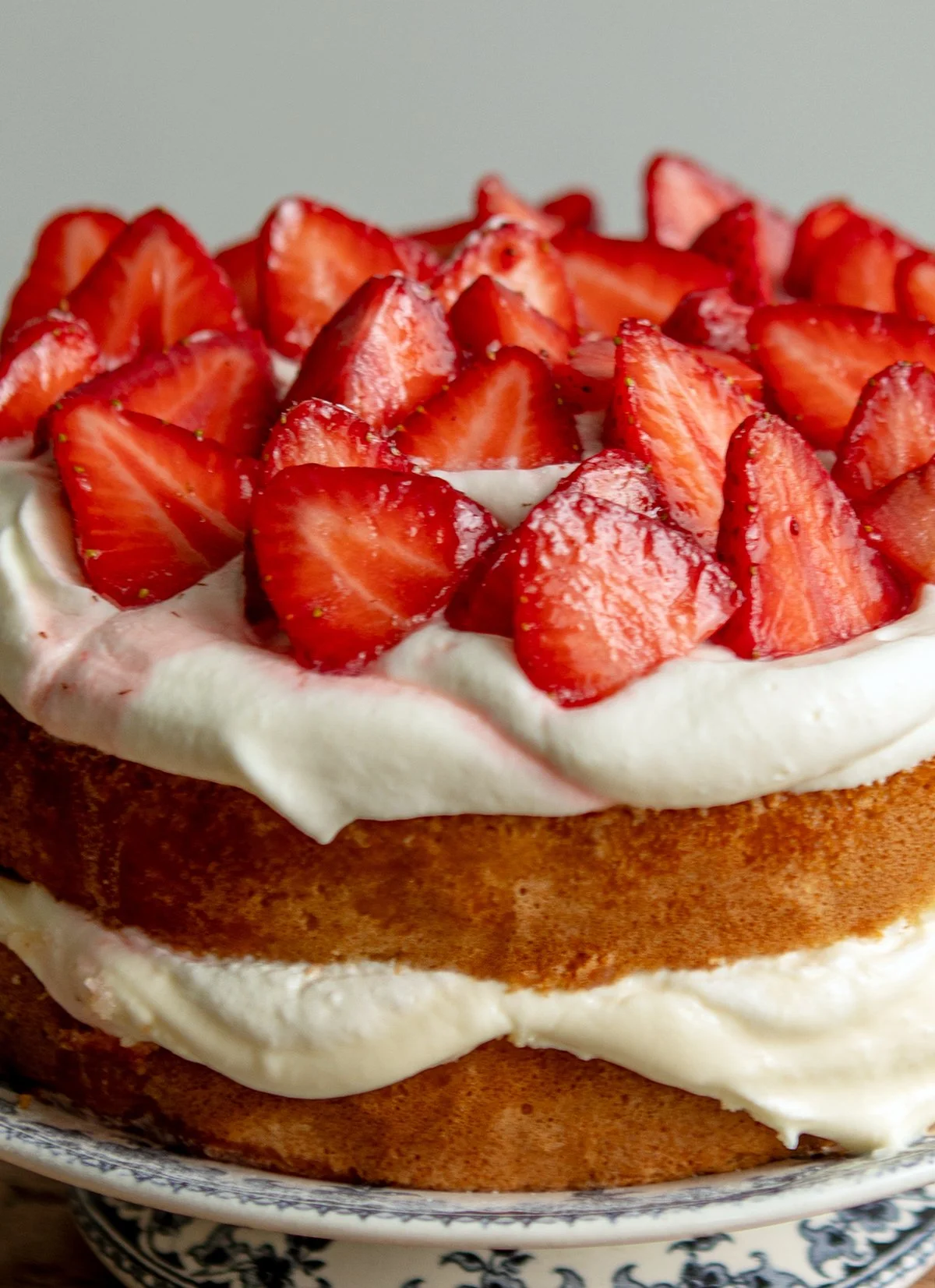 A close-up of a classic strawberry layer cake with whipped cream.