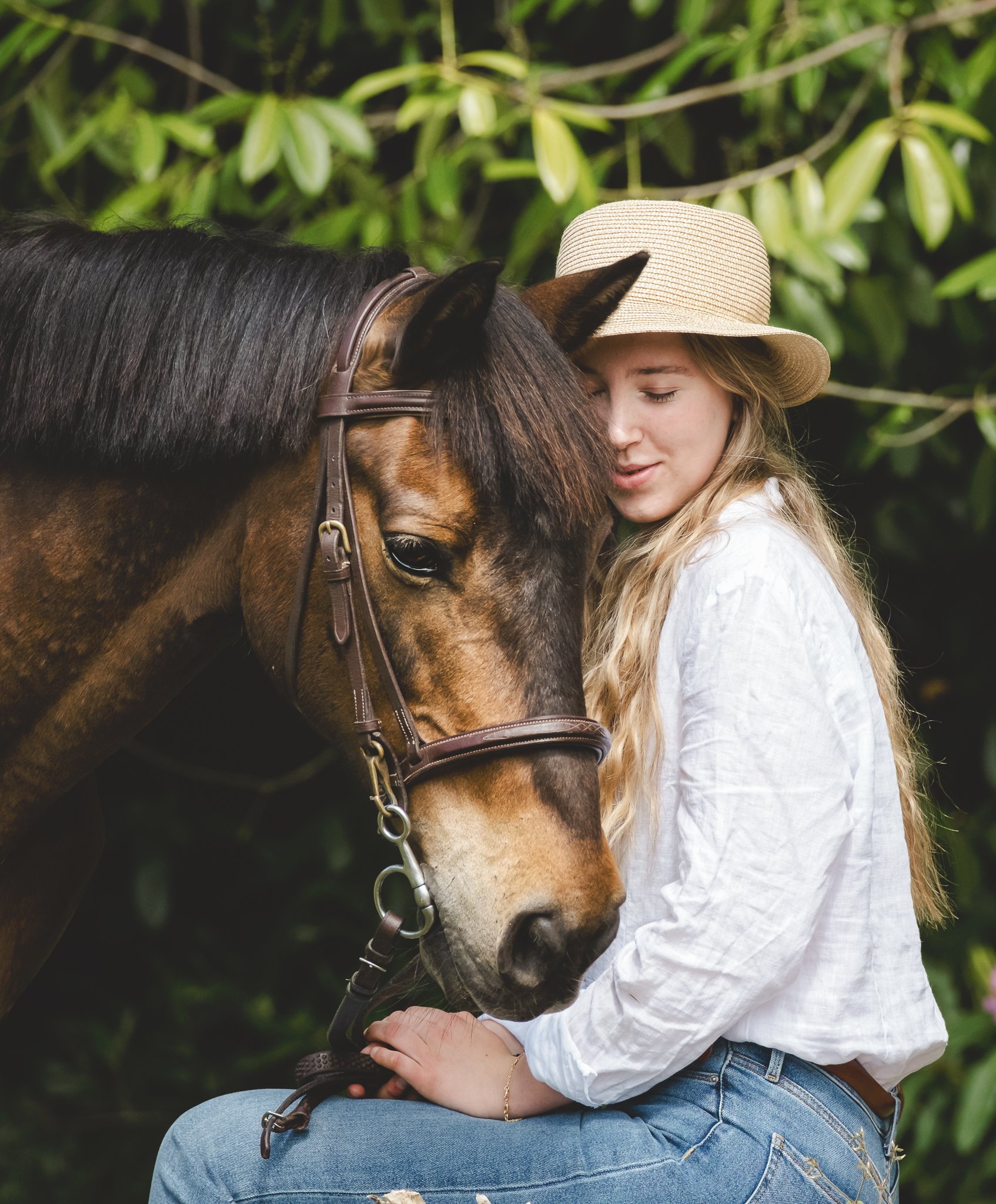 Girl hugging her pony in woodland setting