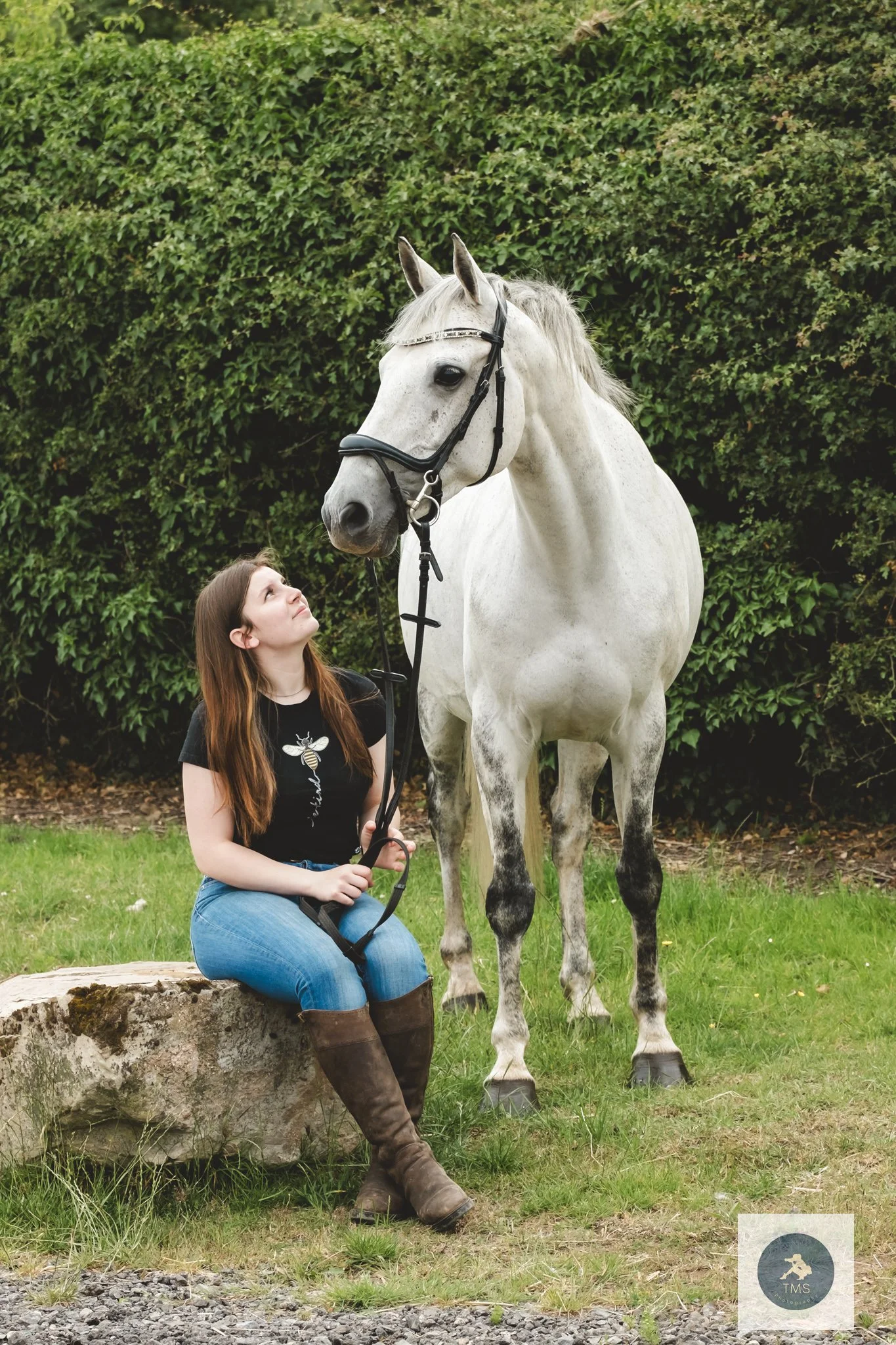Liv sitting on a boulder next to her horse Milly