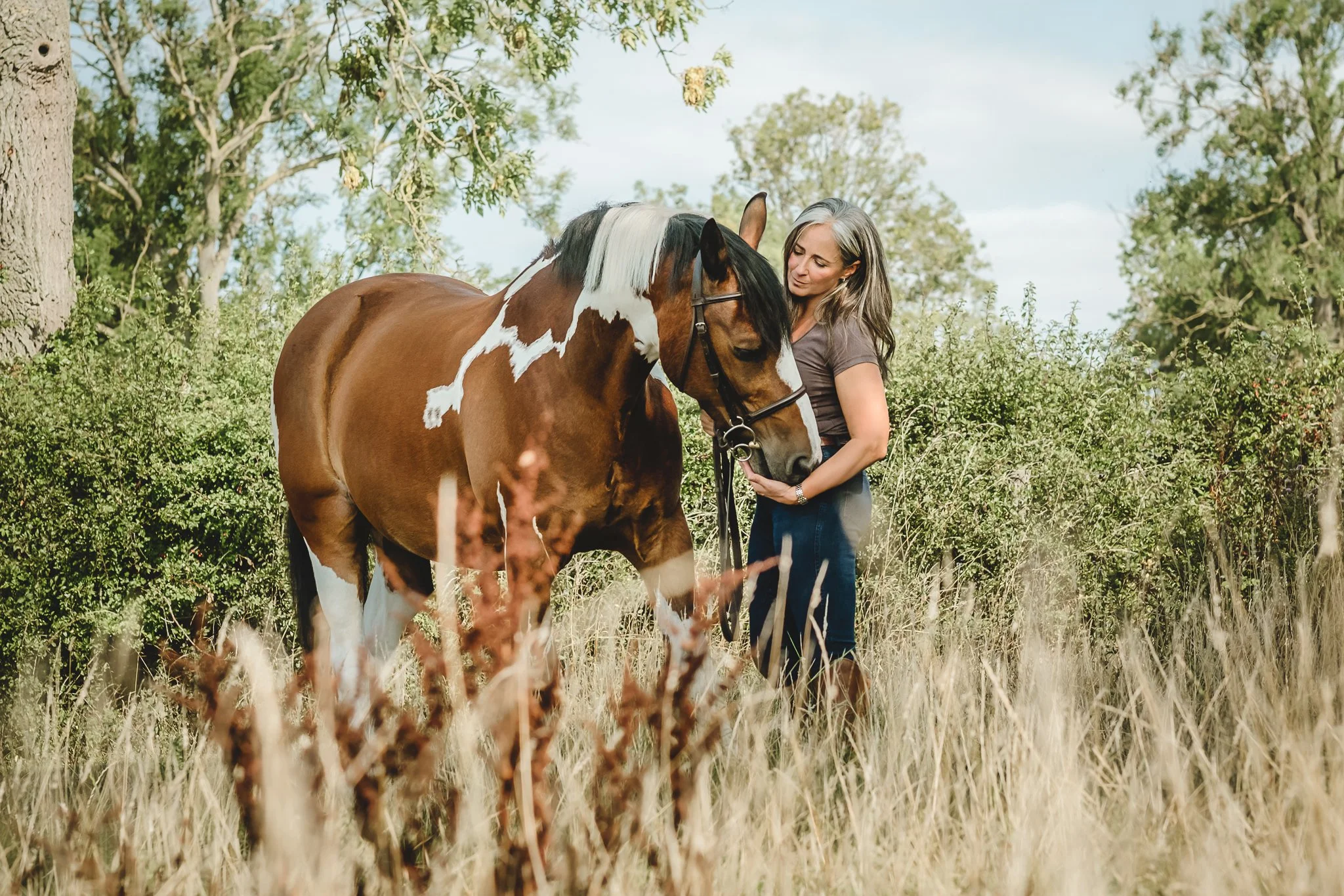 A lady with her skewbold horse during a portrait session early morning in the summer