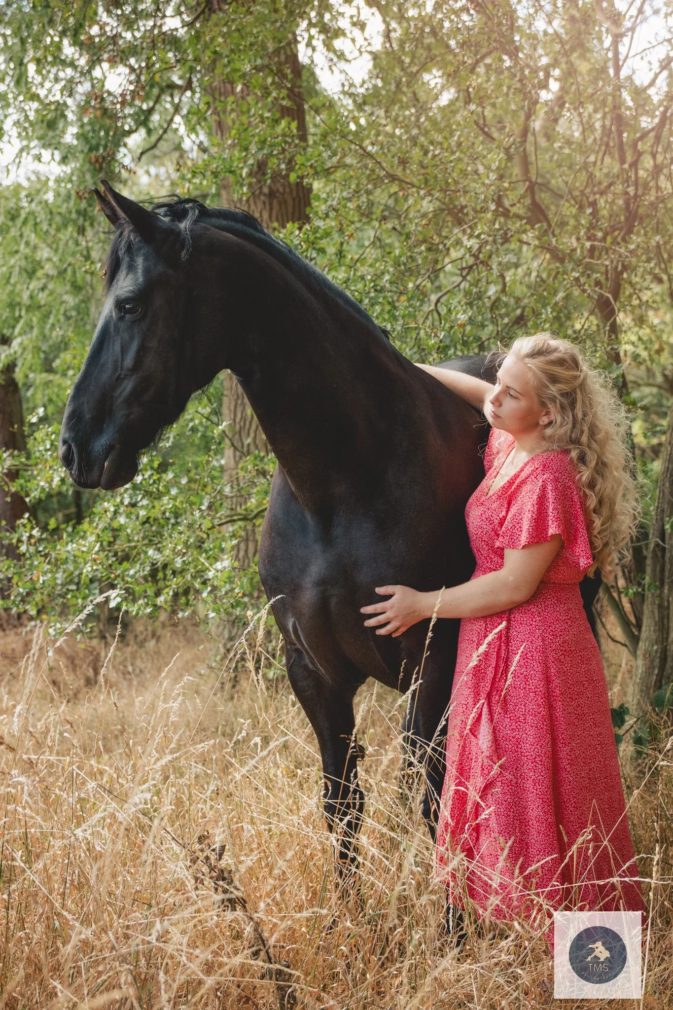Olivia in a floral dress with her black Friesian mare Moike