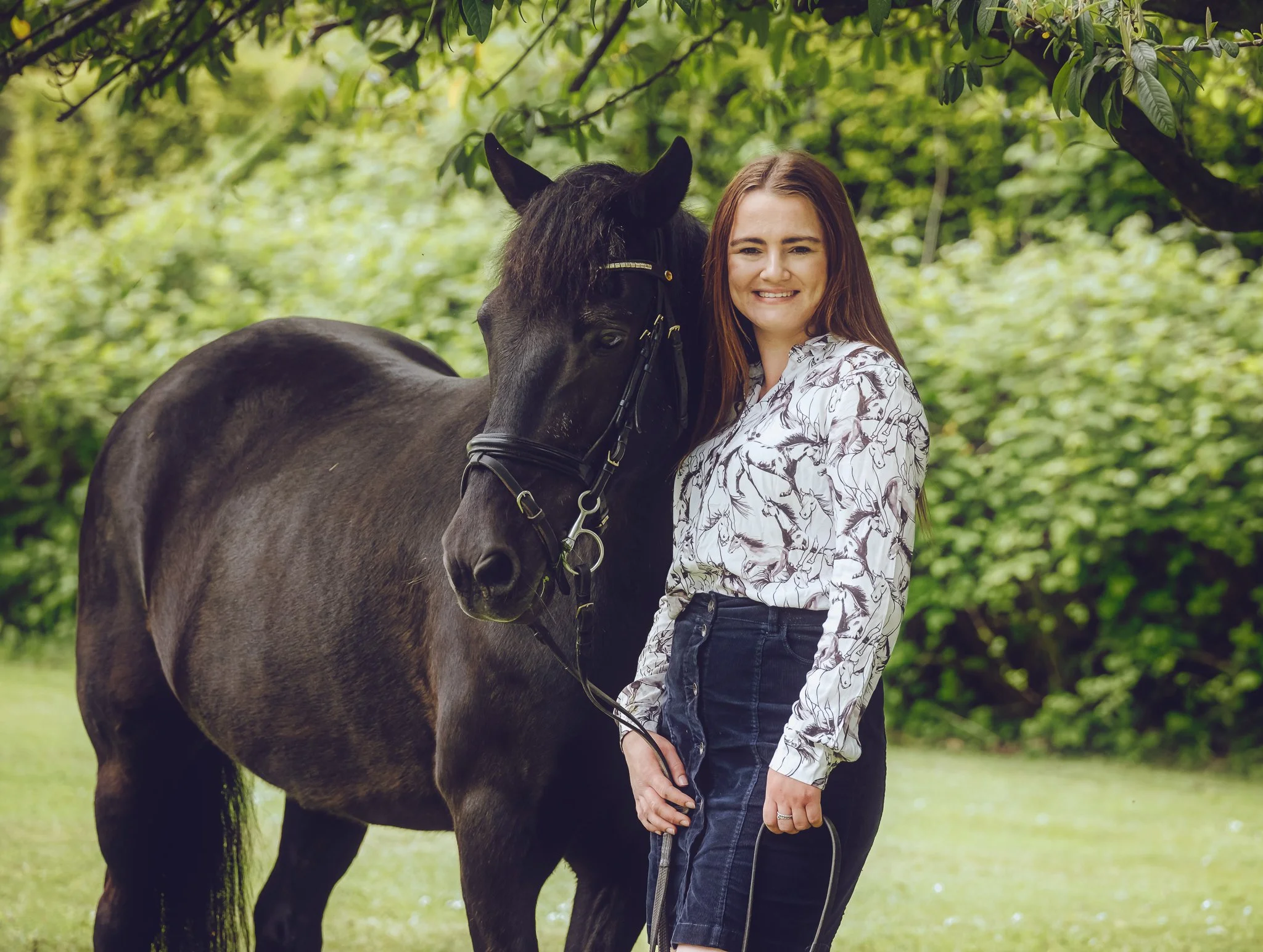a girl standing with her black pony in the new forest