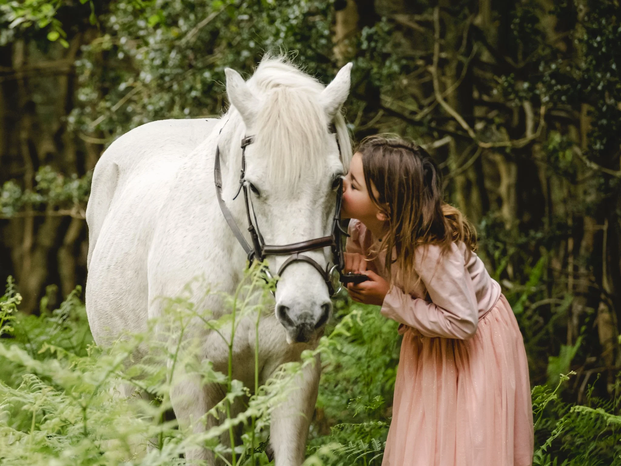 child kissing her pony during countryside photoshoot