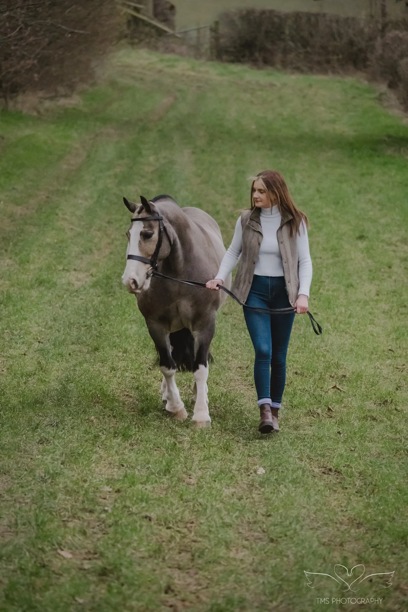 Holly leading buckskin pony Del-Boy on the riding track at her home