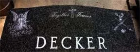 Headstone with the name 'Decker' and motifs of an angel, cross, and deer antlers with arrows.