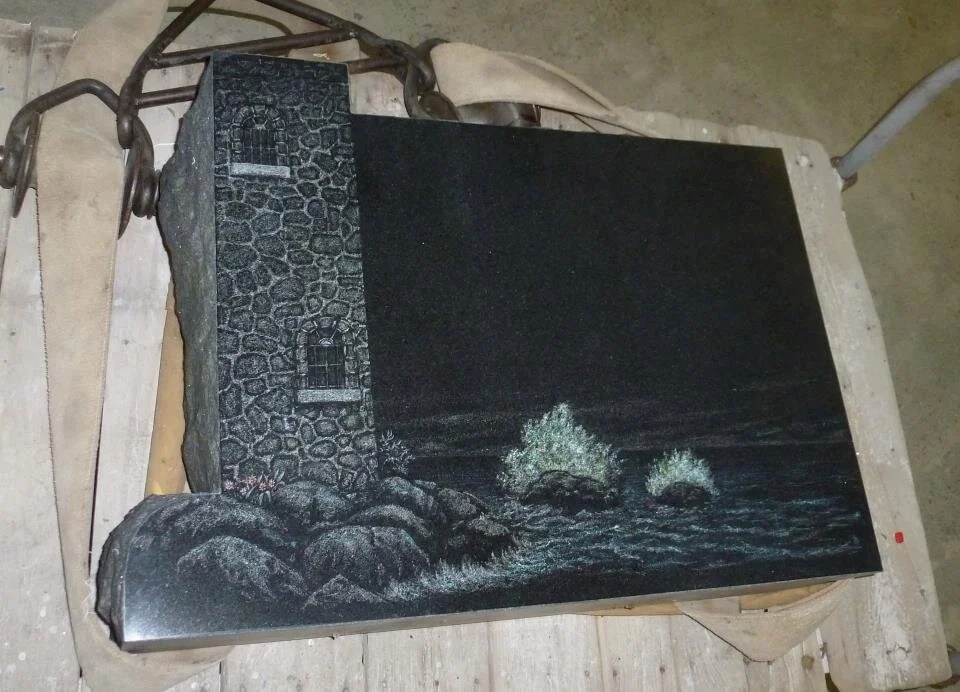 Stone carving of a lighthouse by the sea