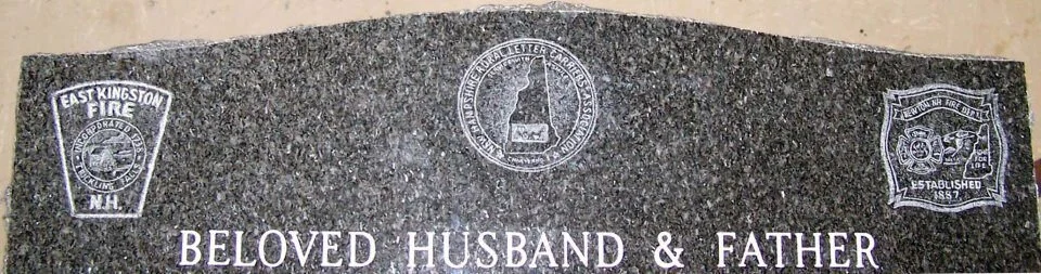 Granite memorial with fire department insignias and the inscription 'Beloved Husband & Father.'