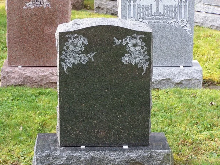 Blank gravestone with floral and bird engravings in a cemetery