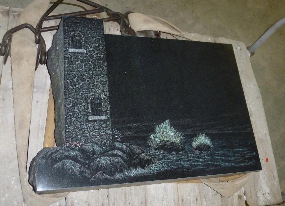 Stone engraving of a lighthouse and ocean waves