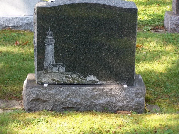 Granite headstone with engraved lighthouse and seascape