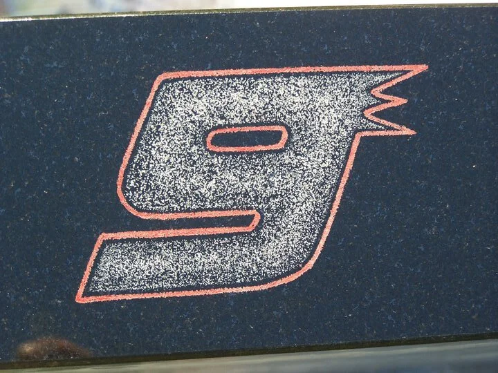 Stylized number 9 with red outline on black surface