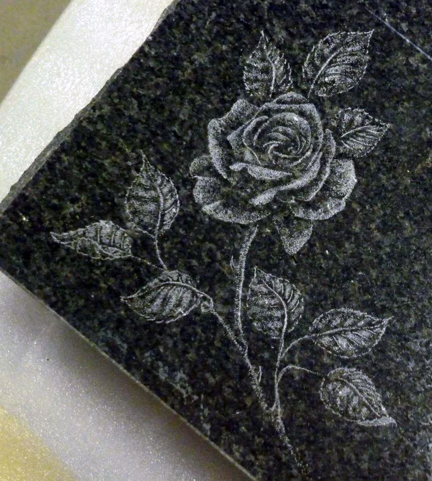 Engraved rose and leaves on dark stone slab