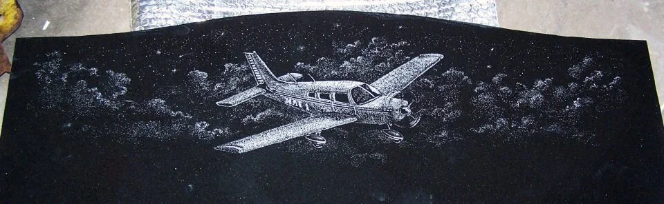 Etched airplane on a black background with cloud patterns.