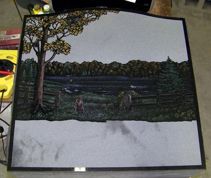 Carved stone memorial with rural landscape scene, featuring a tree, a child, a dog, a fence, and a field under a gray sky.