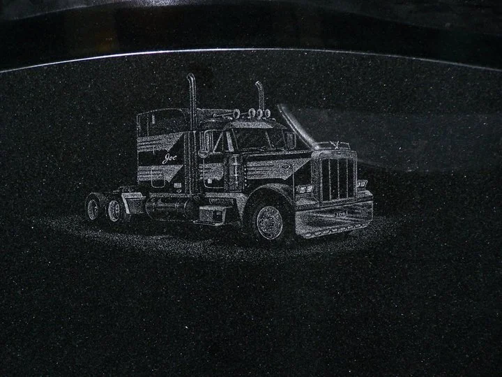 Engraved image of a semi truck on a dark surface.