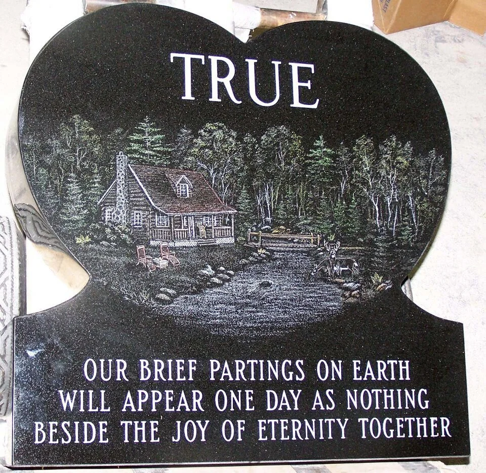 Heart-shaped gravestone with inscription and woodland scene.