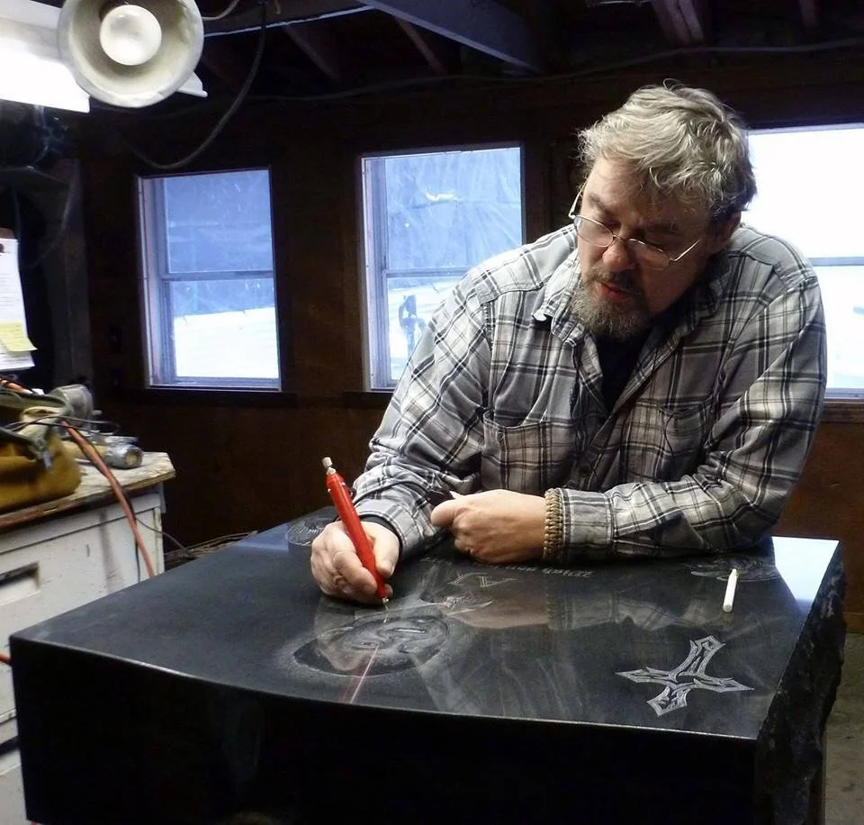Man engraving a black stone slab in a workshop