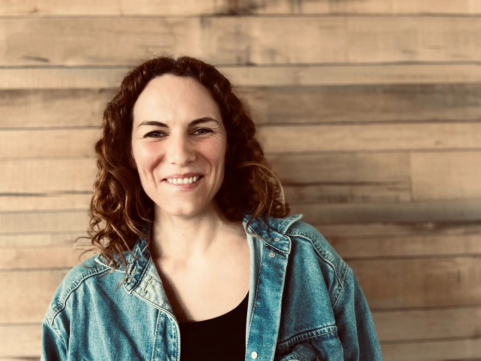 Photo of Lucy Freeman smiling against wooden panel wall