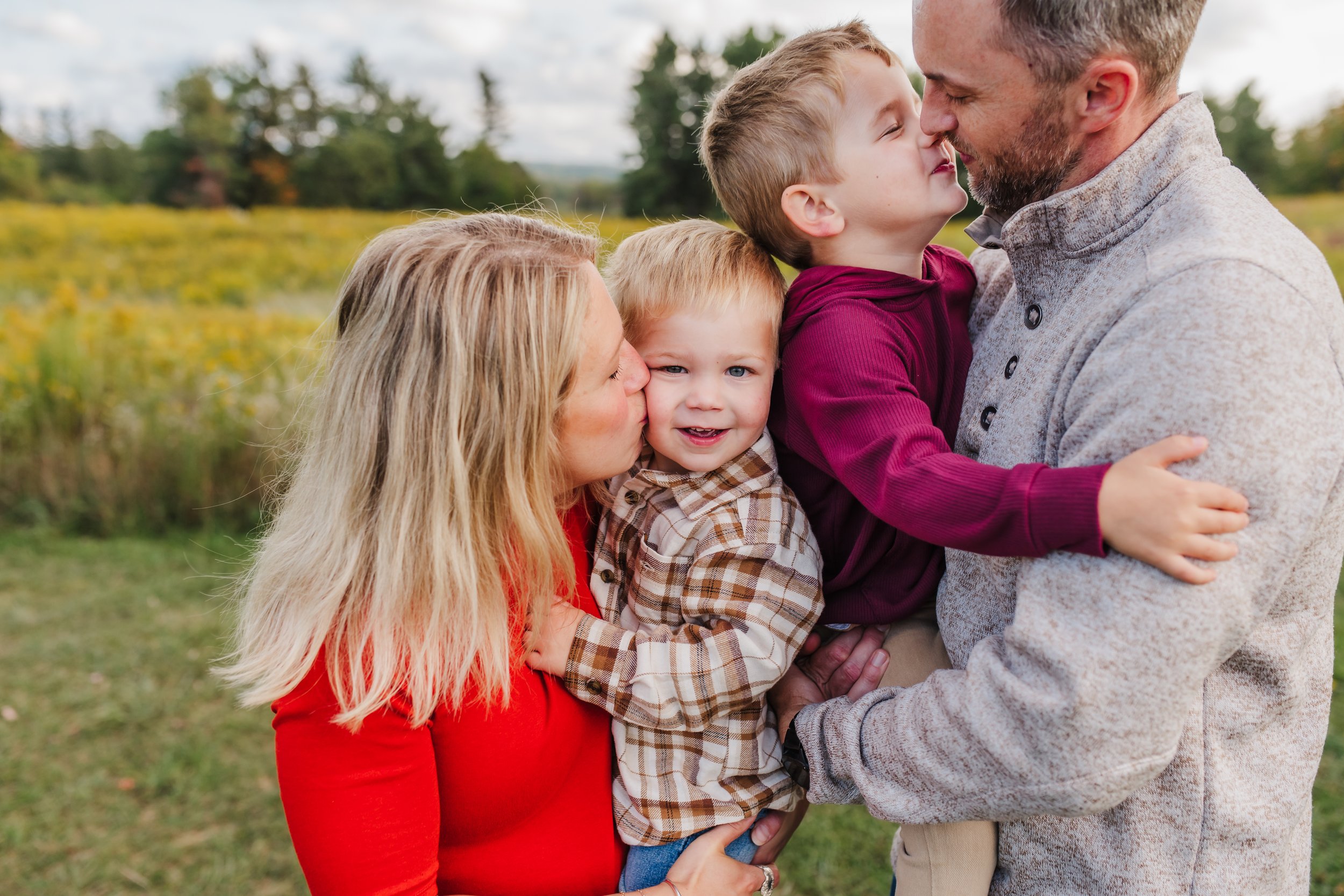parents with two sons hugging and kissing at Knox Farm in East Aurora
