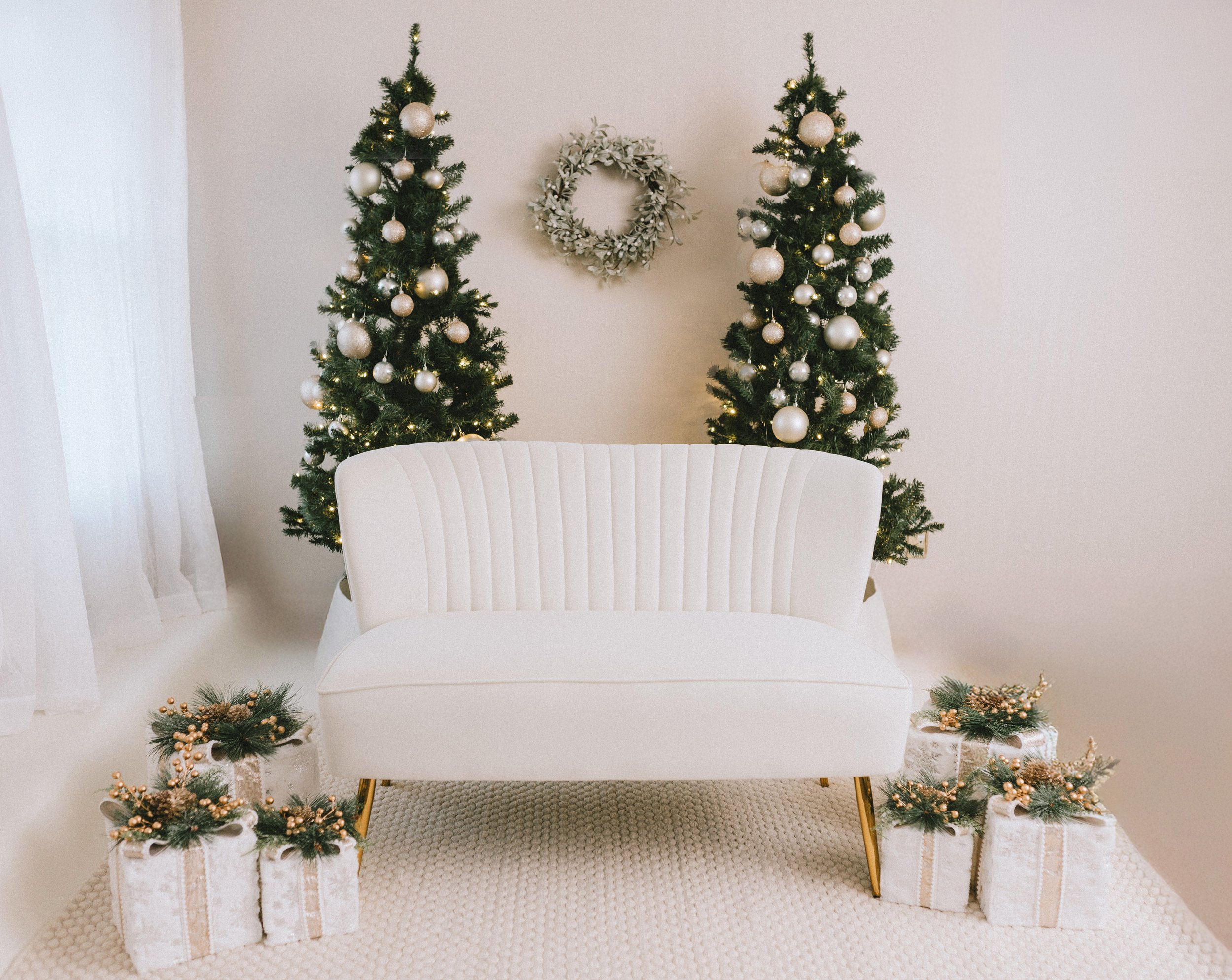 Holiday scene with white loveseat and Christmas trees and gifts