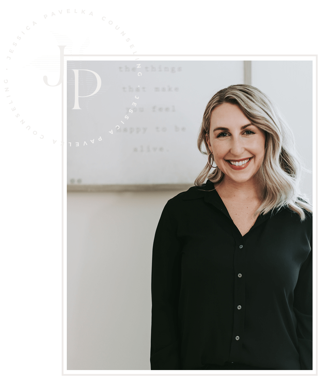 A woman with blonde hair wearing a black blouse smiling in front of a whiteboard with writing on it