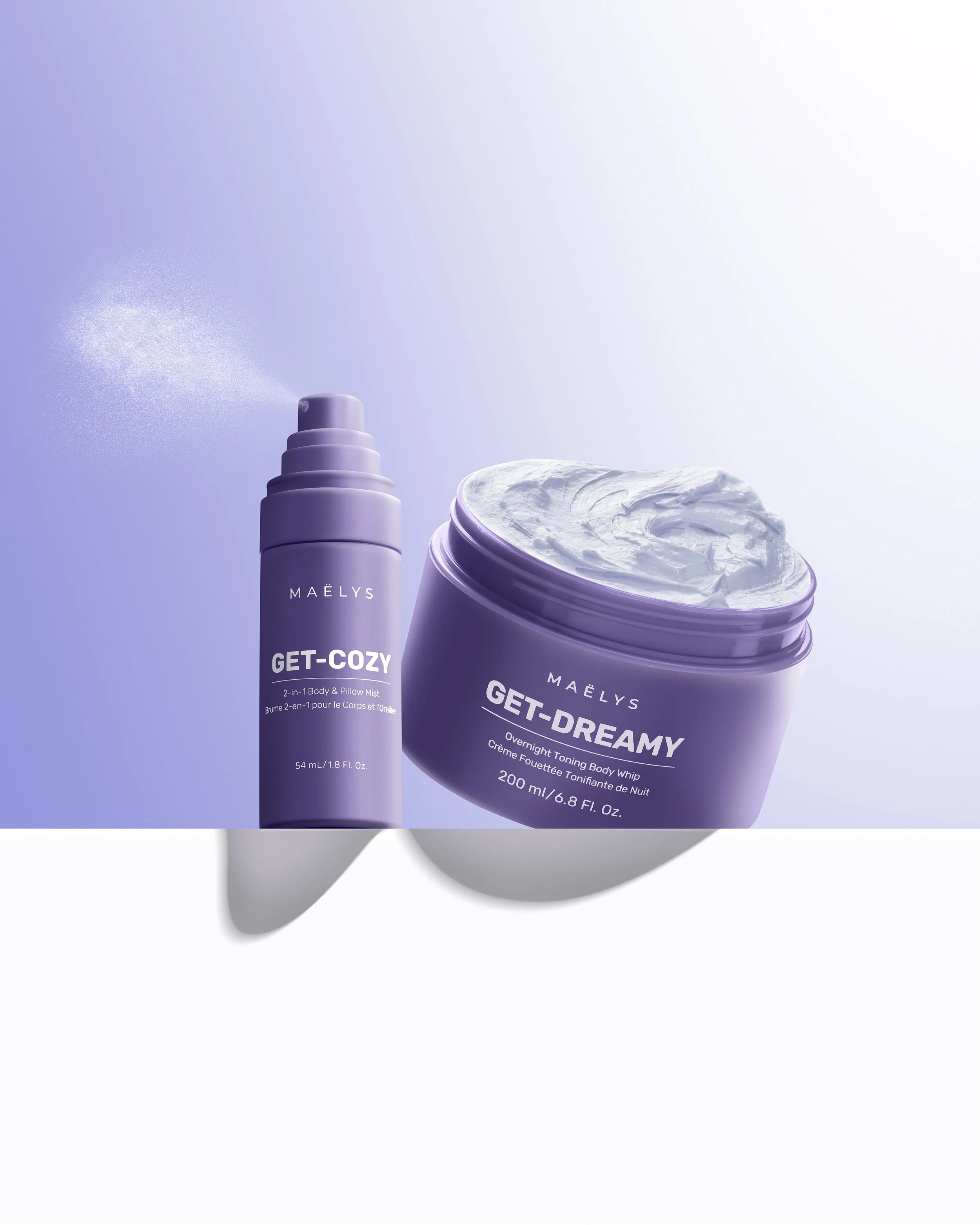 Two skincare products in purple containers: a spray bottle labeled 'GET-COZY' and an open jar labeled 'GET-DREAMY' with white cream inside, set against a light blue background.