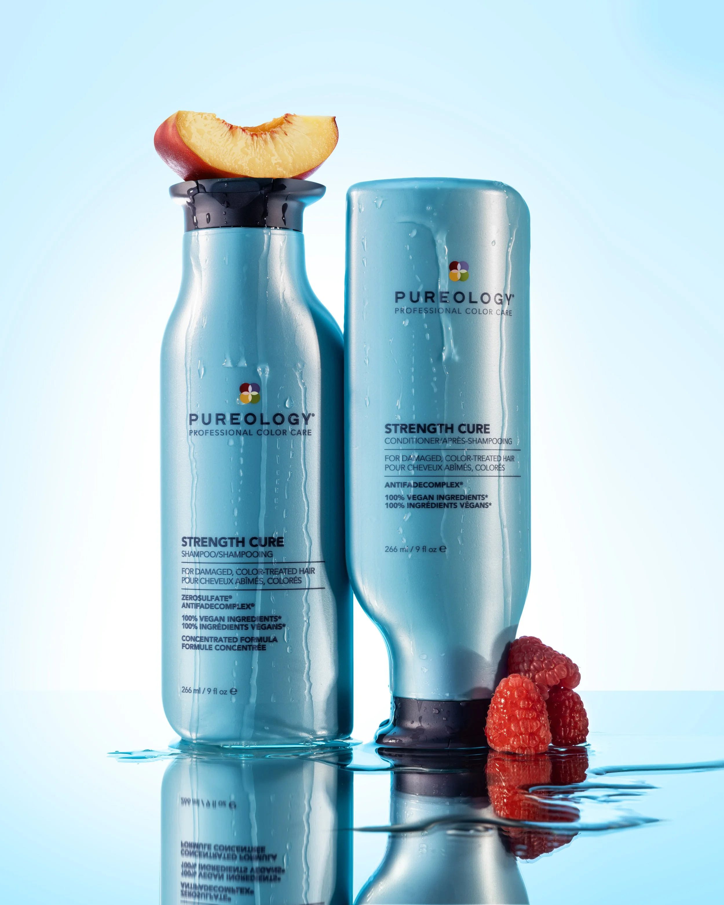 High-end beauty product photography of skincare bottles with water and fresh fruit accents. Pureology.