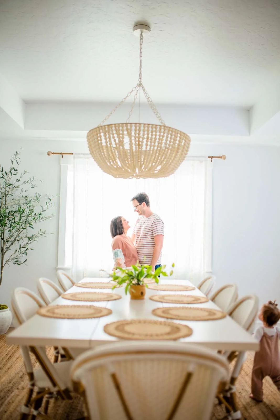 Photo taken as a in home family photo session. Parents embrace in their lovely home in Nampa, Idaho while child runs to greet them.