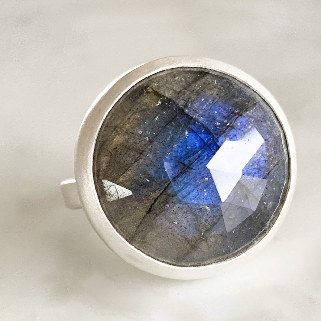 A substantial rose-cut Labradorite, a stone thought to impart strength and perseverance, rests inside a handcrafted bezel forged from sterling silver and sits atop a silver band. Available now @shopcarmilias in size 5.75 &amp; size 8. $350. Stunning 