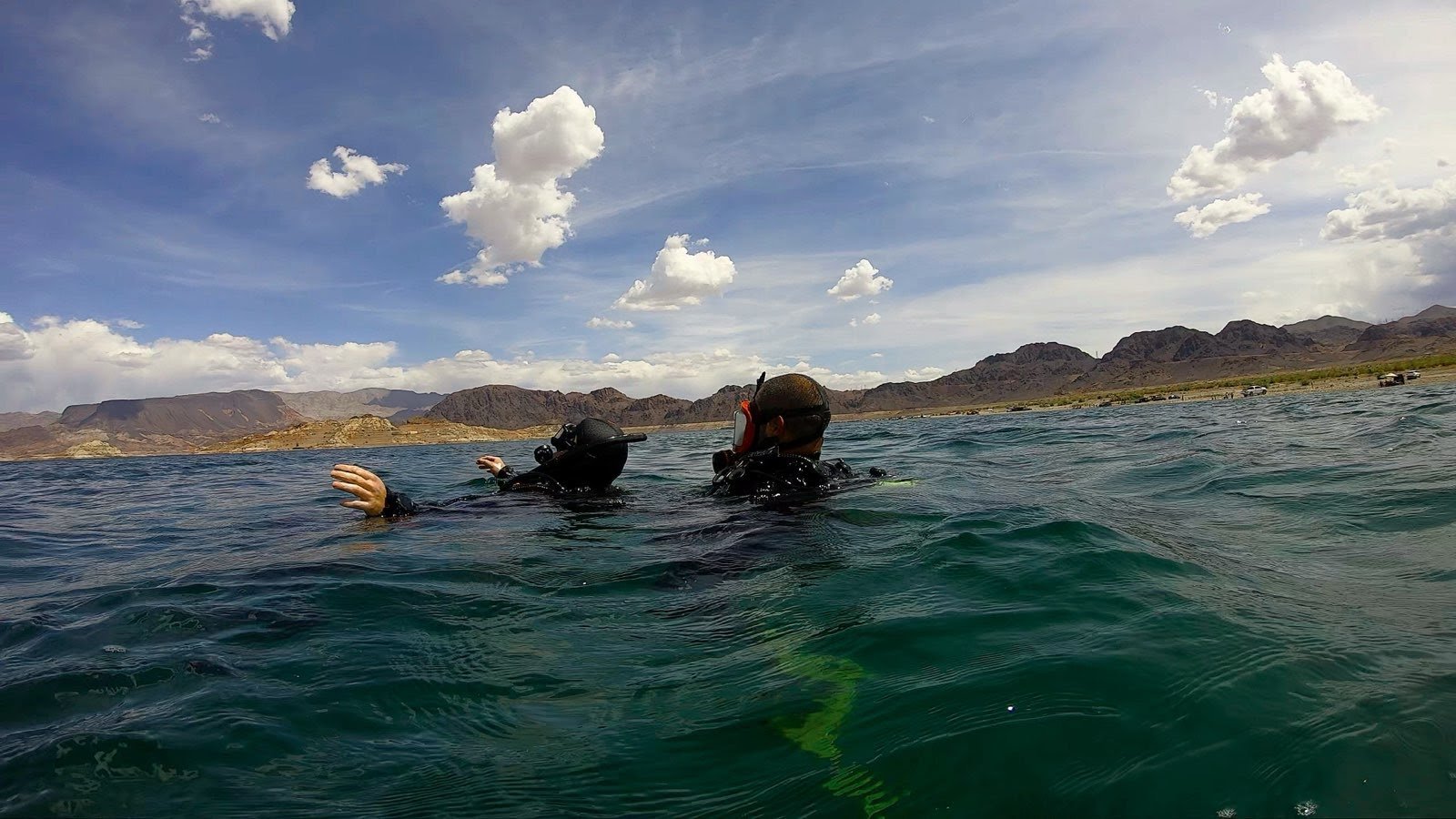 Person in black wetsuit floating face down in a swimming pool with a snorkel and fins.