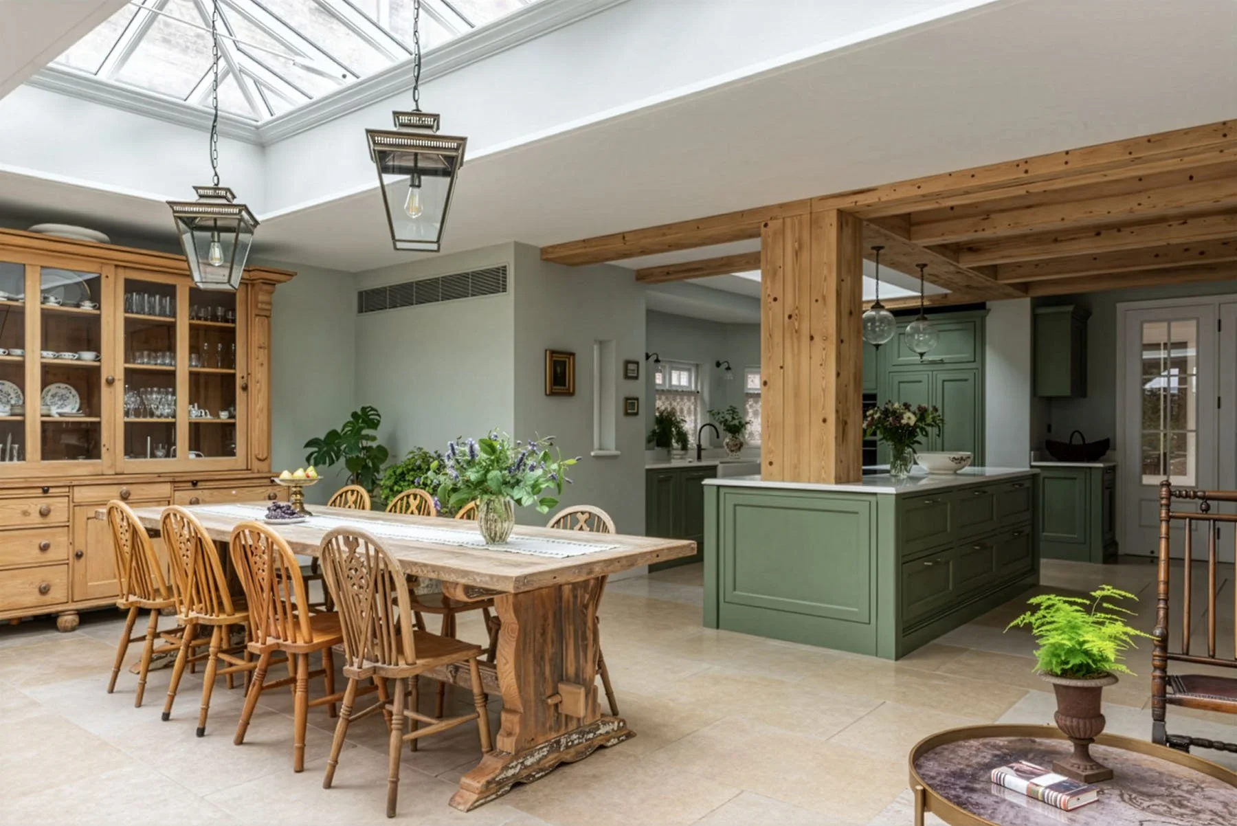 Open-concept kitchen and dining area with wooden table, chairs, green cabinets, and skylight ceiling.