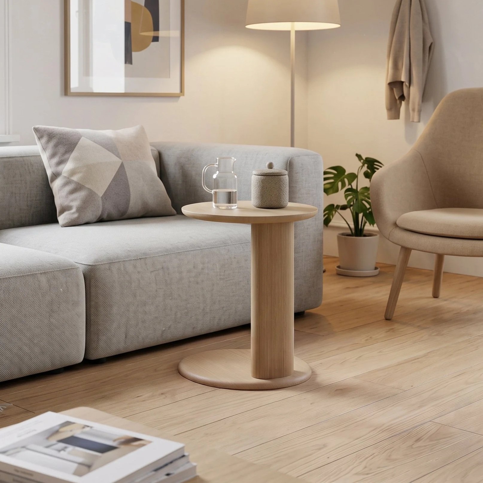 A living room with a light gray sofa, decorative pillow, wooden side table with a glass water pitcher and a small container, beige armchair, potted plant, floor lamp, and abstract artwork on the wall.