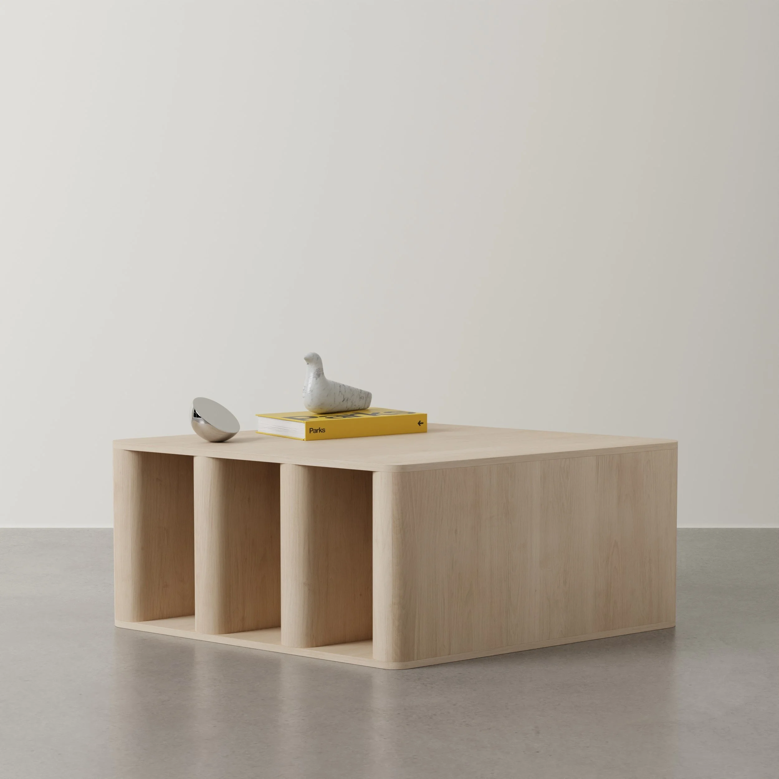 A minimalist wooden shelving unit with a beige wall in the background. On top of the shelf, there is a potato-shaped sculpture, a book titled 'Parks' on a yellow surface, and a modern oval-shaped object, possibly a speaker or decorative item. The sce