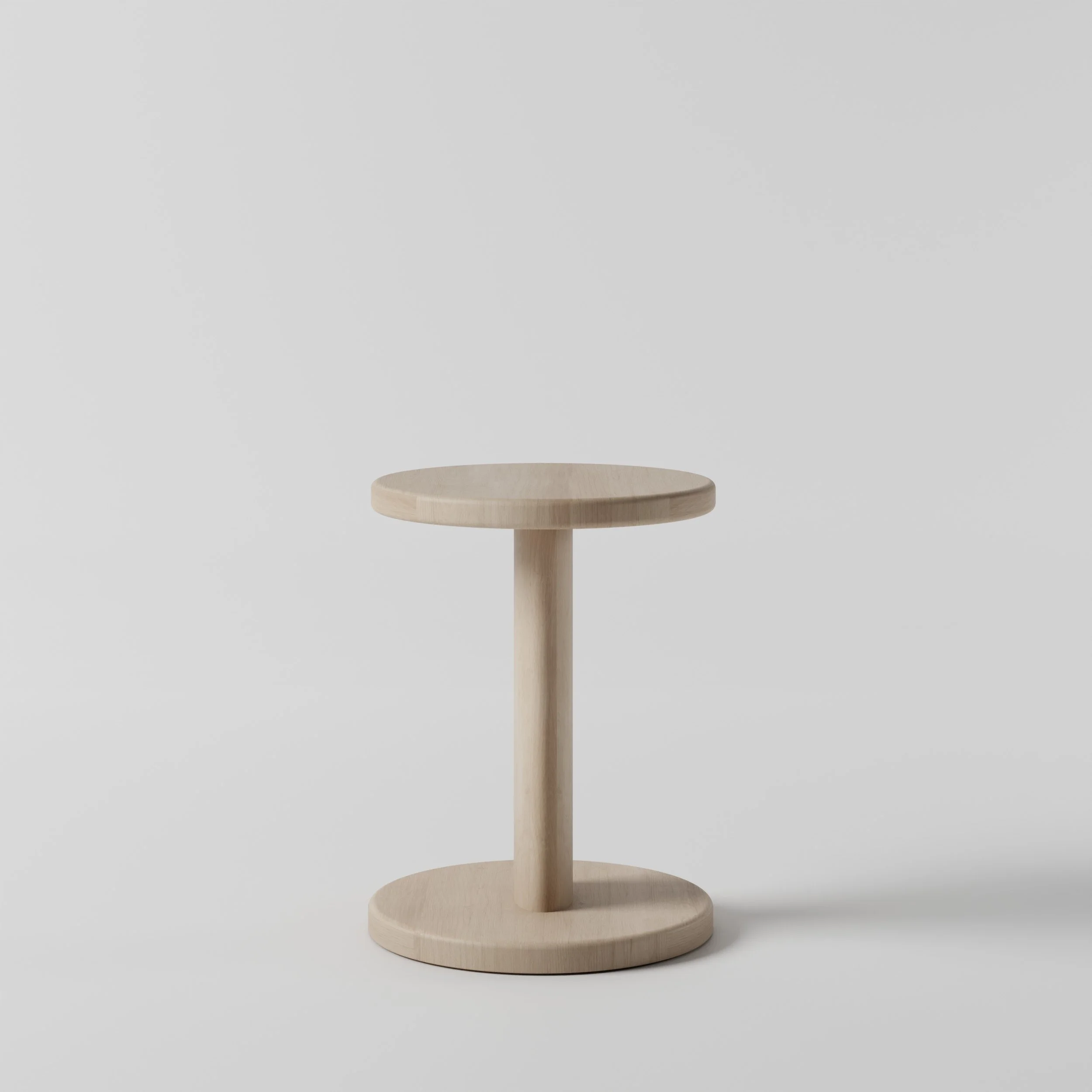 A wooden low stool with a round top and a single central support, set against a plain light gray background.