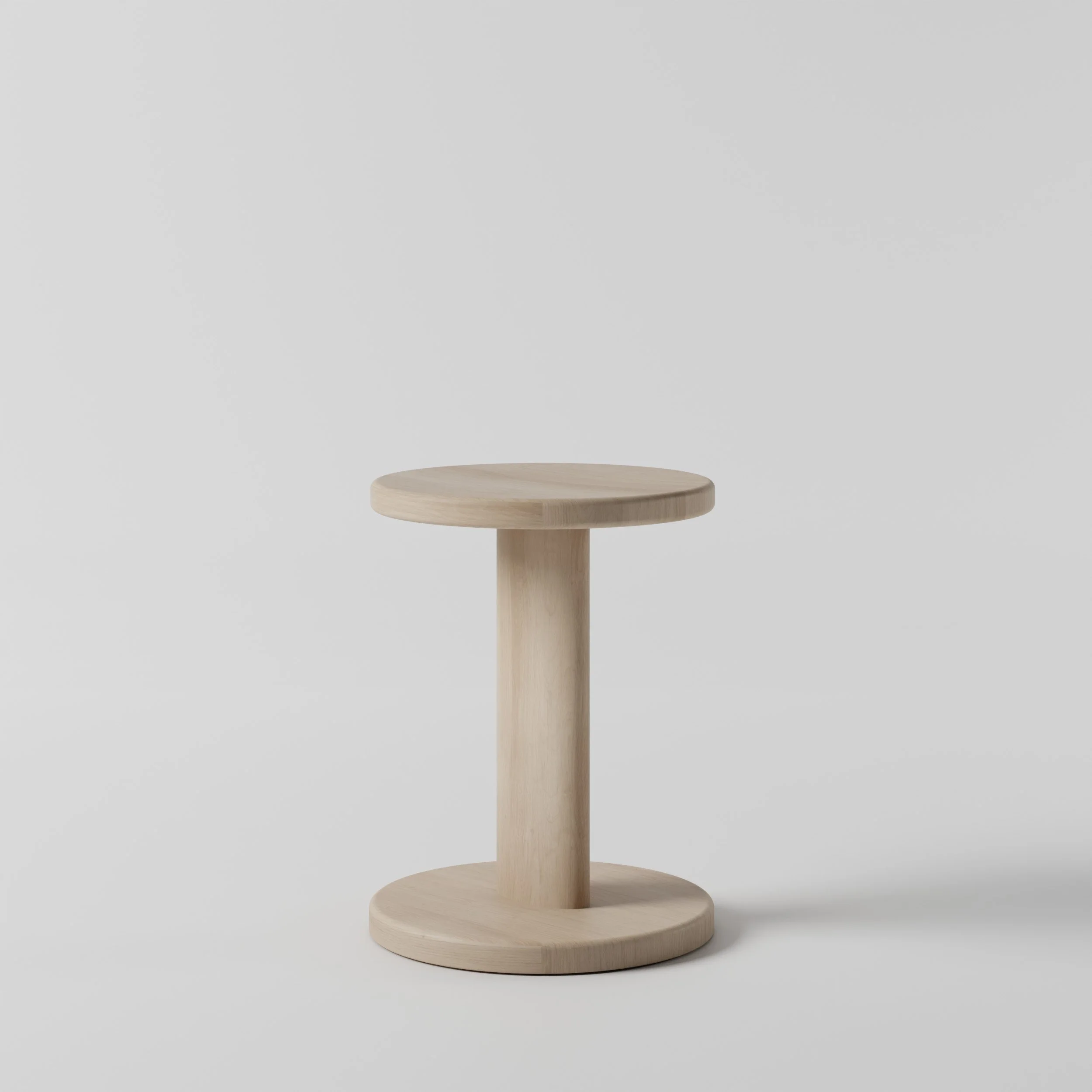 A light wooden round stool with a central supporting pole and flat round base against a plain gray background.