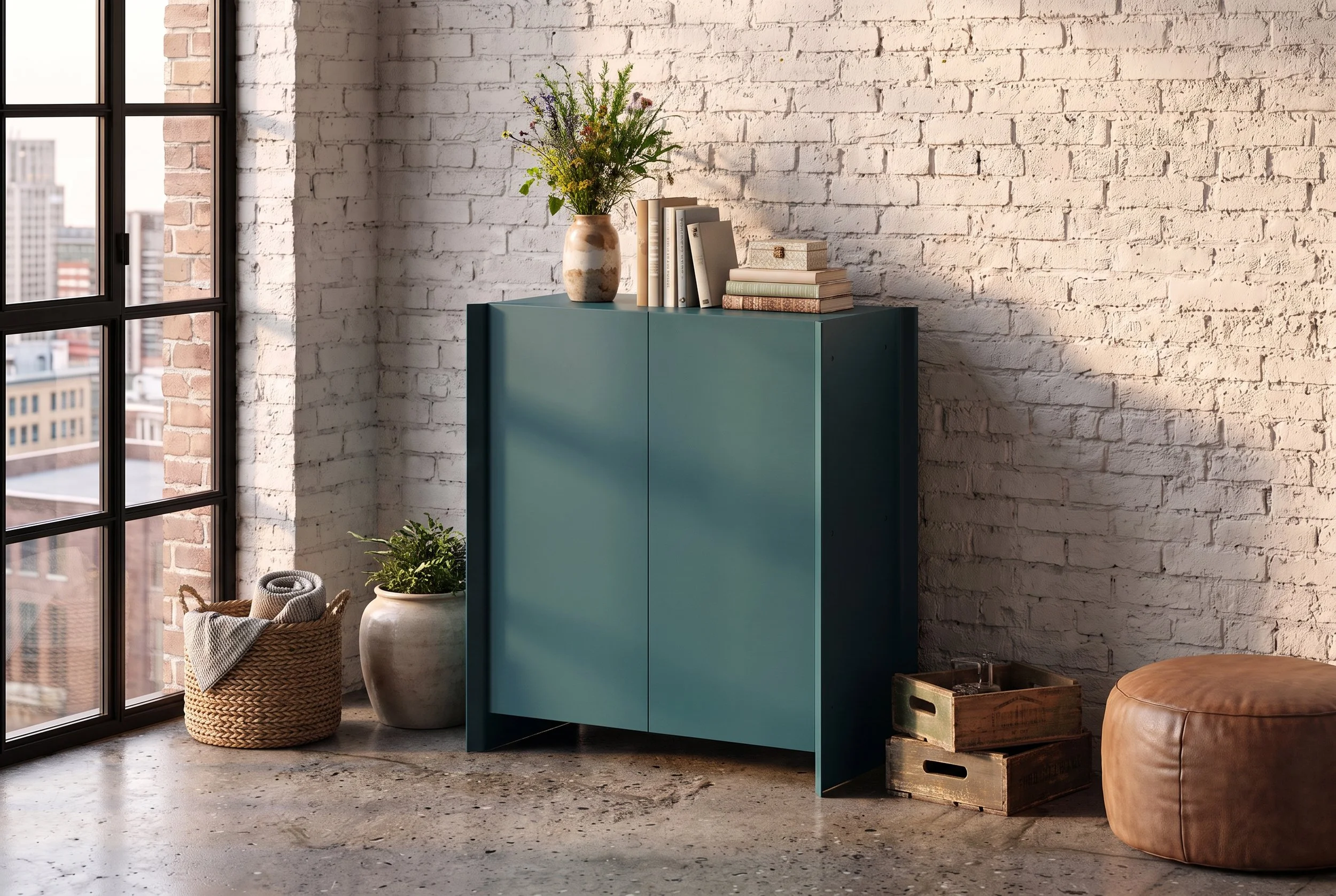 Interior of a modern room with a large window, a white brick wall, and a teal cabinet decorated with books and a vase of flowers. There is a basket with a blanket and a plant on the floor, and a brown leather pouf with a wooden crate beside it.