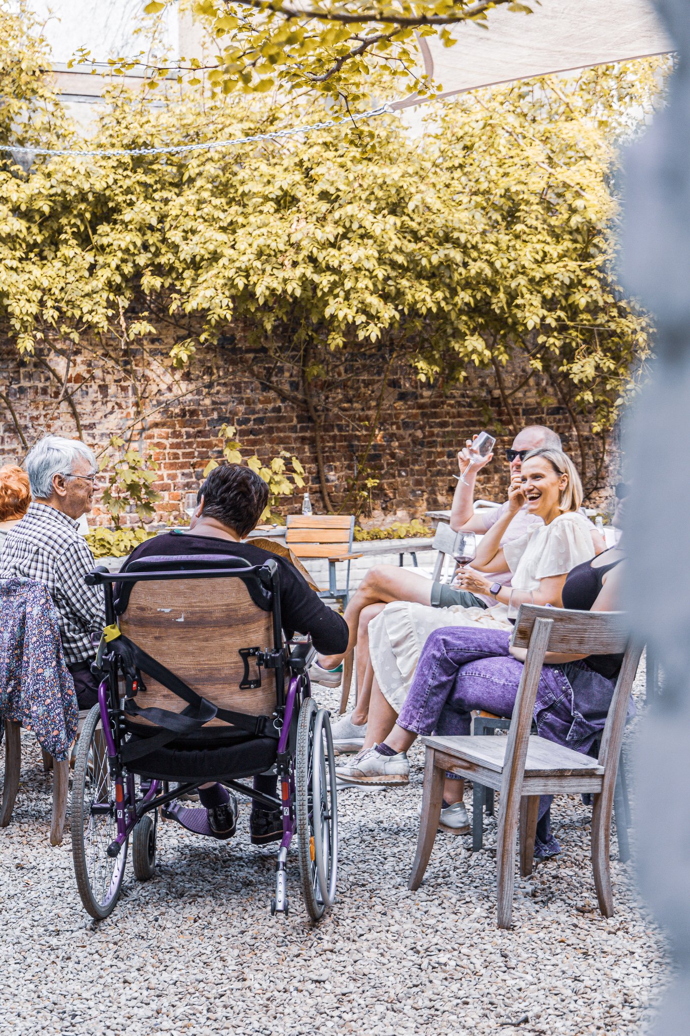Groep mensen in een tuin, zittend en pratend op een familiefeestje