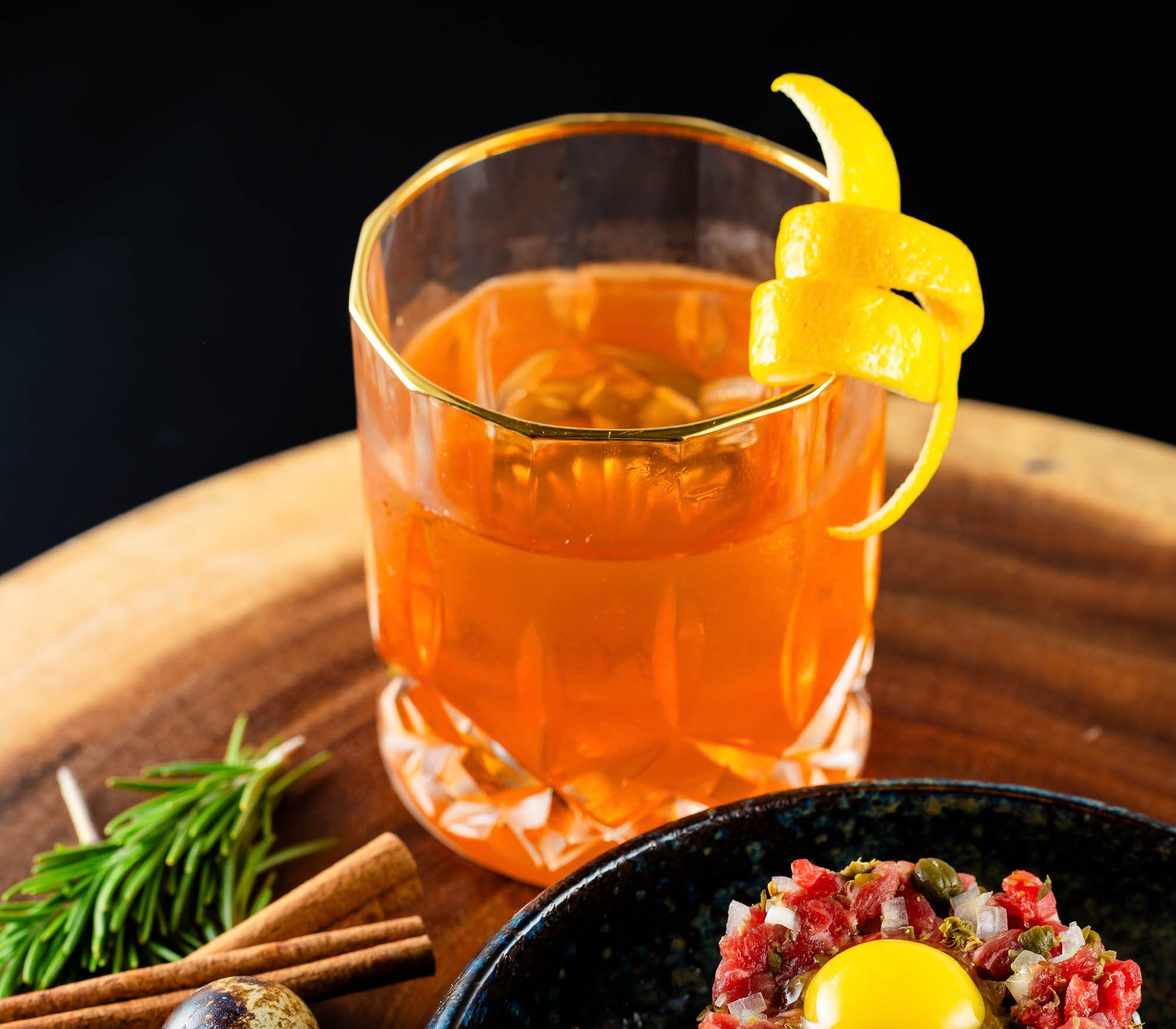 Harvest Spice Punch, lemon twist, orange cocktail, rocks glass, sage, cinnamon stick, beef tartare