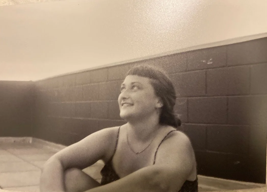 A portrait photo in vintage style of CAF’s Support Coordinator Lucy (a white person with short bangs) looking up to the up left corner and smiling in a tank top