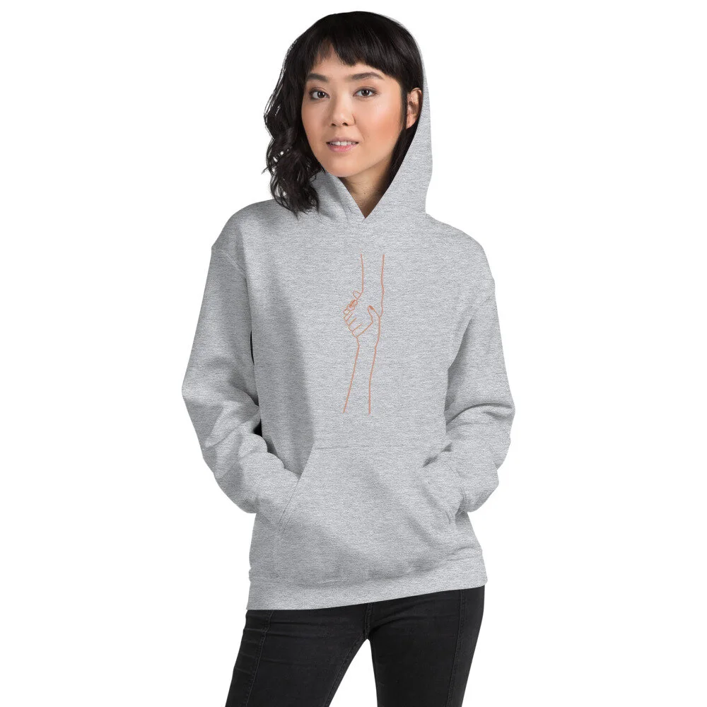 woman in a light grey hoodie with pockets and line illustration of one hand lifting up another