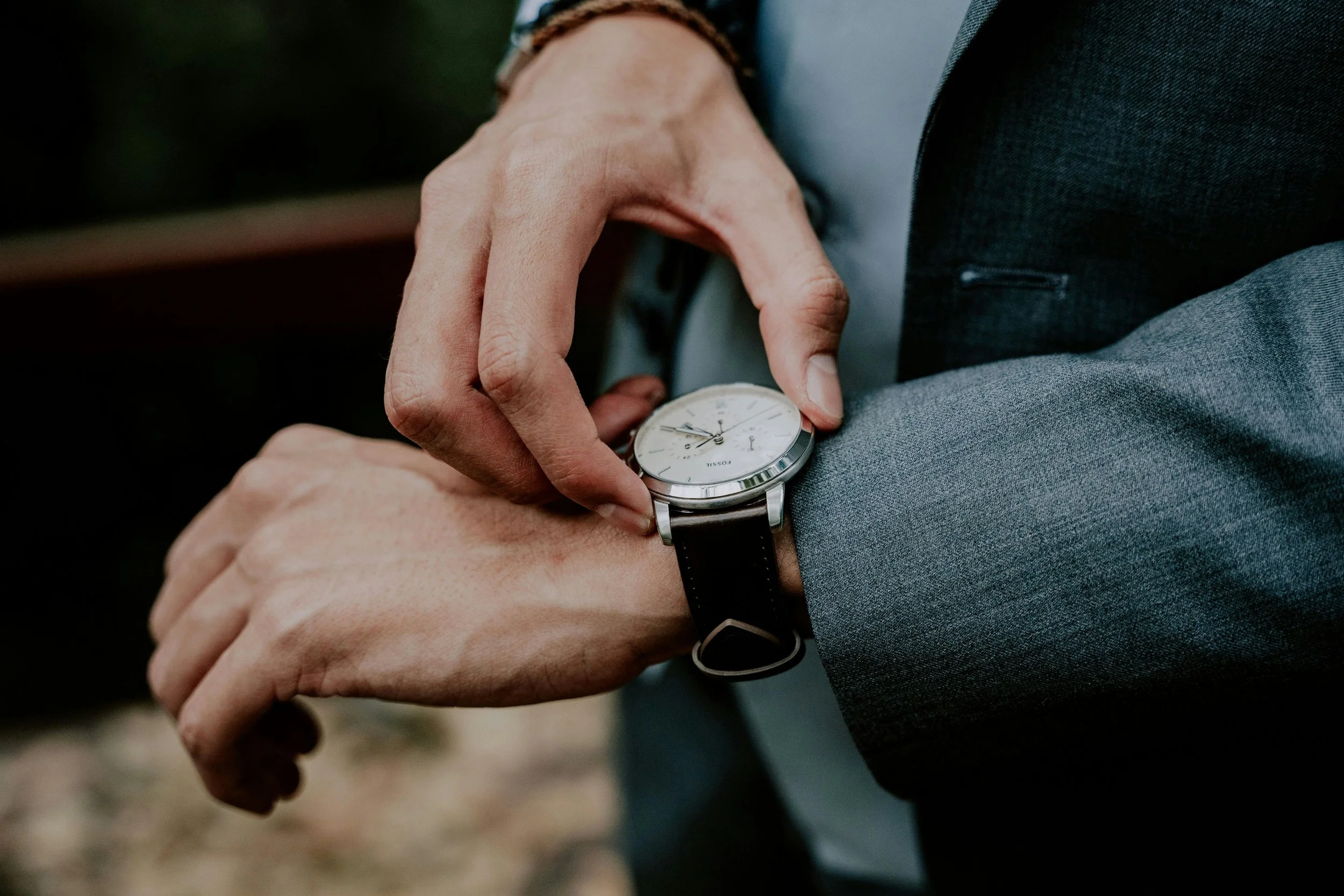 A person in a business suit checking the time on their wristwatch.
