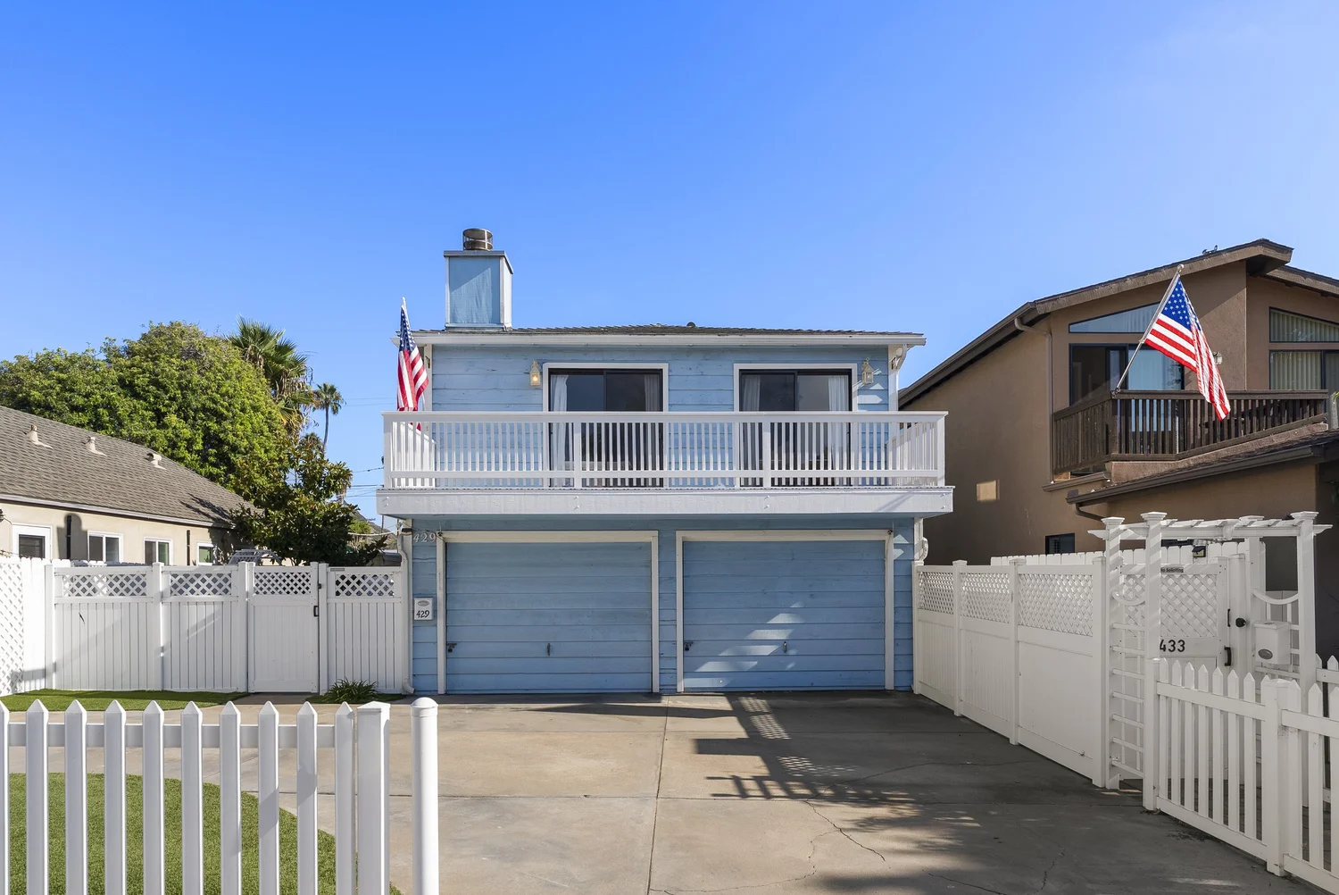 Street view of 429–433 Nautilus St: the light-blue front home with two garages and a white picket fence