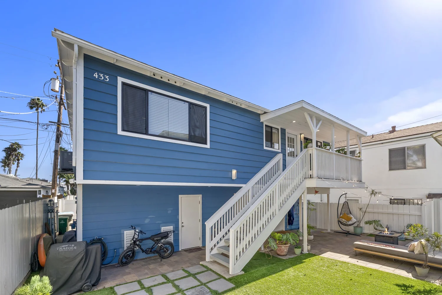 Rear home exterior with blue siding, stairs and lawn