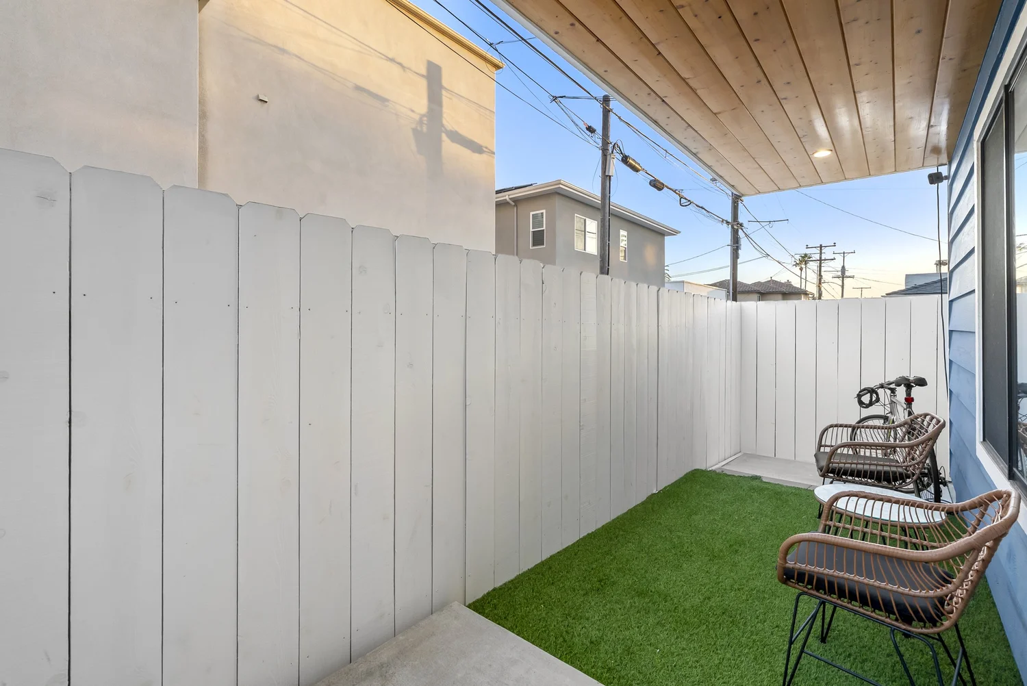 Private side yard with artificial turf and patio chairs