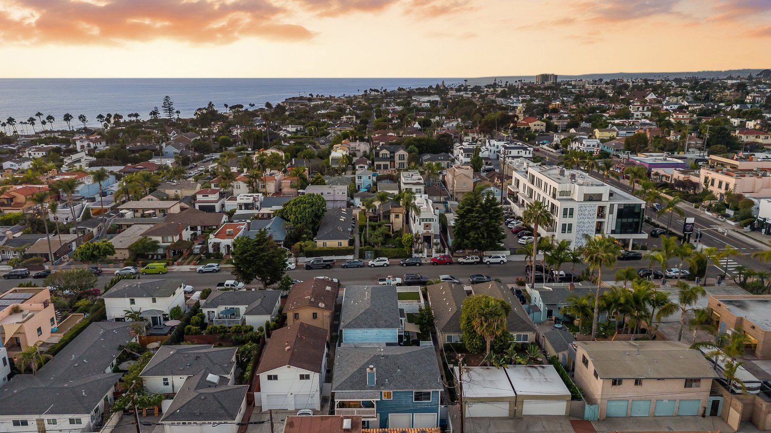 Aerial over La Jolla rooftops toward the ocean at dusk