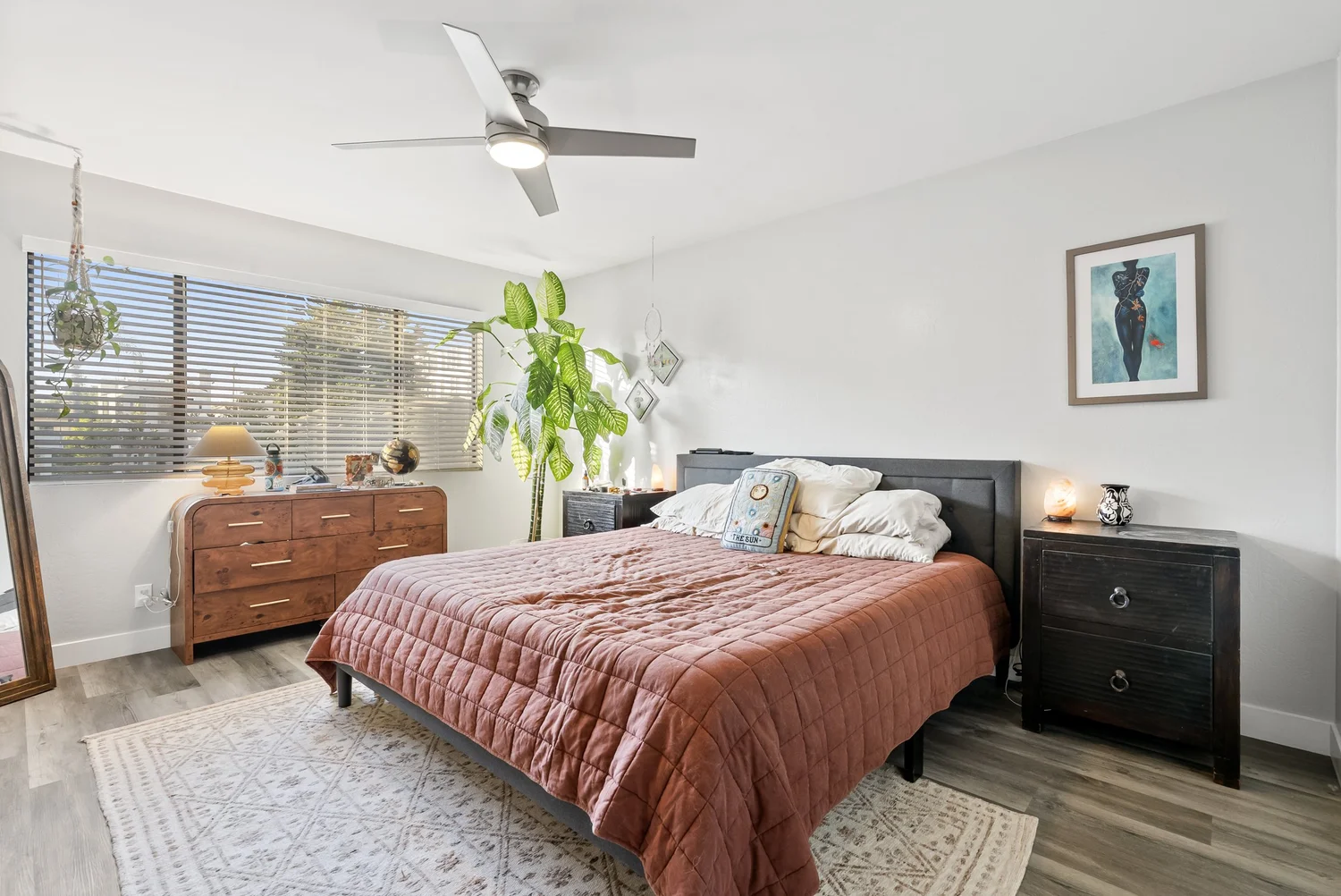 Bedroom with rust-colored bedding and wood dresser