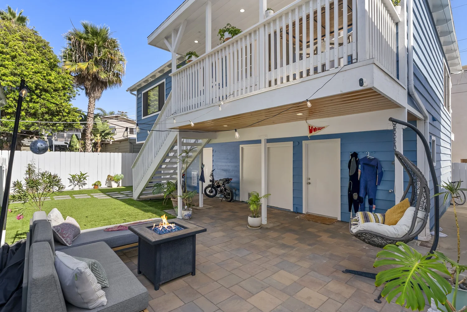 Rear home patio with outdoor seating, lawn and stairs to the upper deck