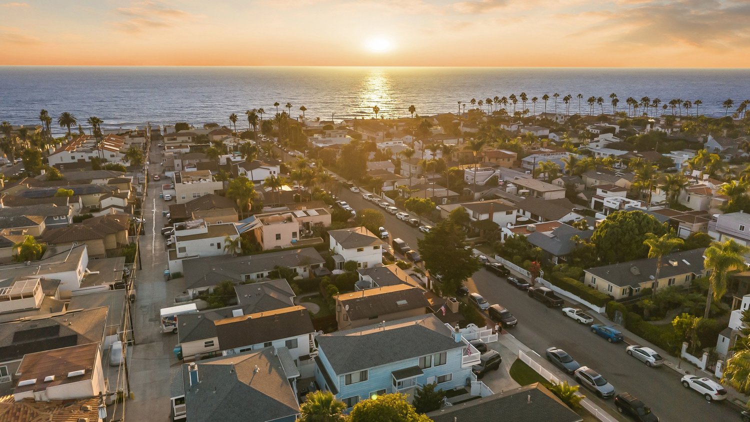 Aerial over La Jolla's coastal neighborhoods toward the ocean at sunset